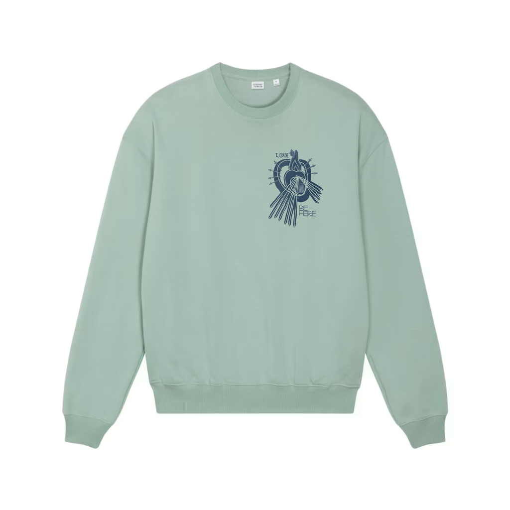 An Aloe green crewneck sweatshirt shown from the front, featuring an indigo blue graphic print of a little human heart enclosed in the womb of the Sacred Divine Mercy Heart of Jesus enclosed in the womb of Immaculate Sorrowful Heart of Mary wit the words LOVE and BE HERE