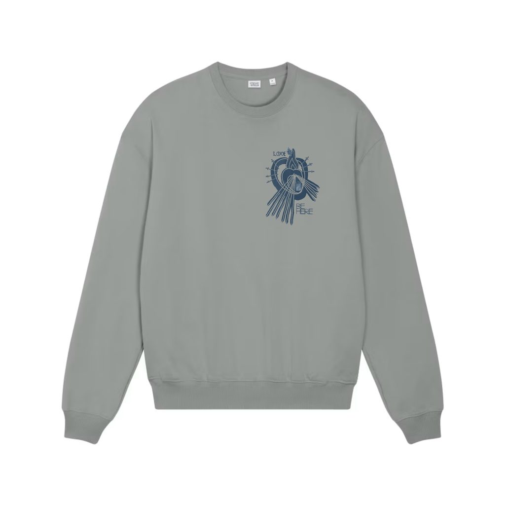 A misty gray crewneck sweatshirt shown from the front, featuring an indigo blue graphic print of a little human heart enclosed in the womb of the Sacred Divine Mercy Heart of Jesus enclosed in the womb of Immaculate Sorrowful Heart of Mary wit the words LOVE and BE HERE